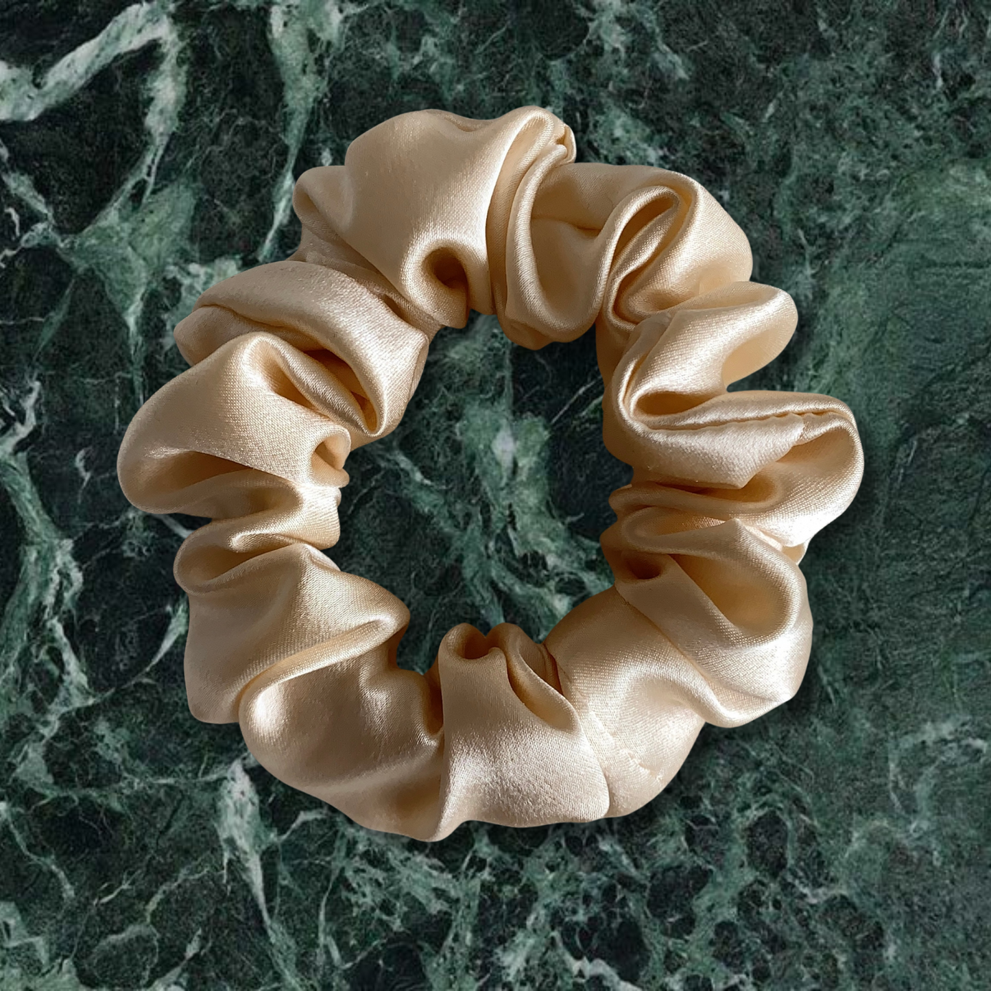 Champagne large scruchie on green marble background.