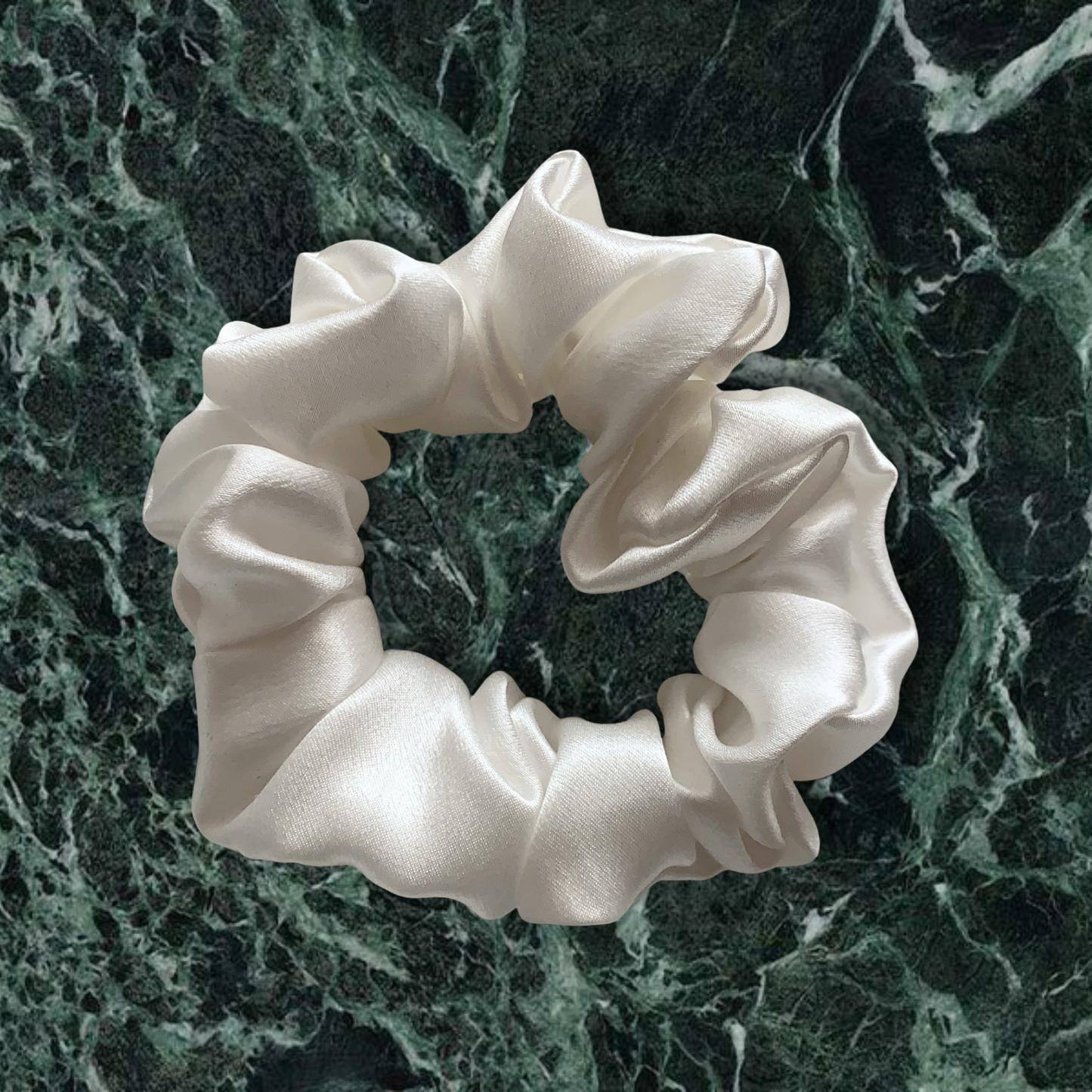 White large scrunchie on green marble background.