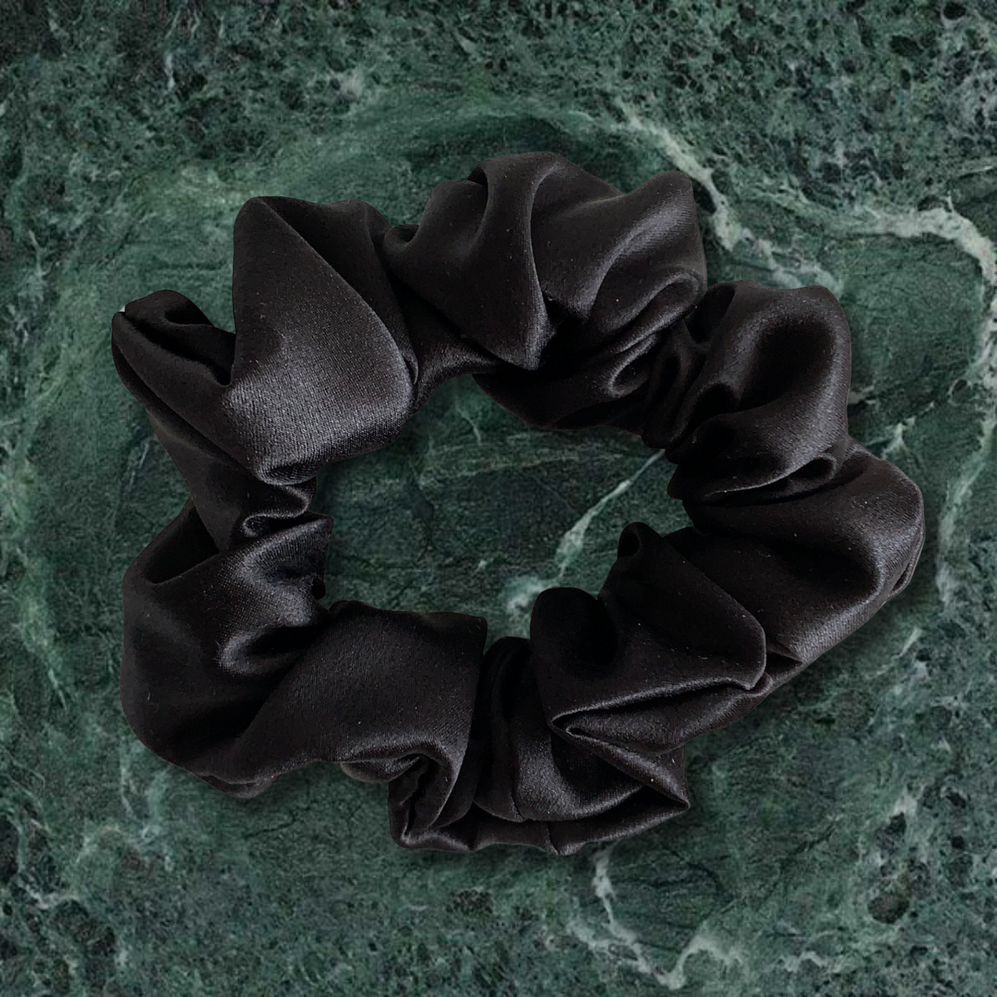 Black large scrunchie on green marble background.