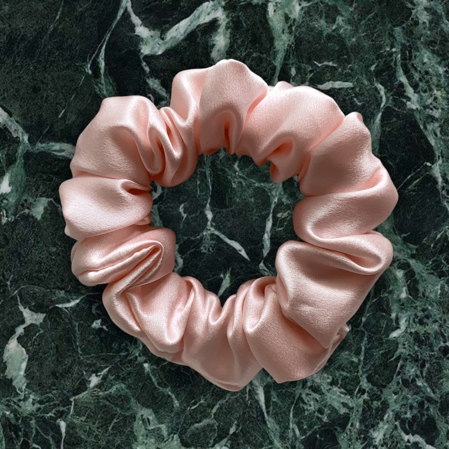 Pink large scrunchie on green marble background.