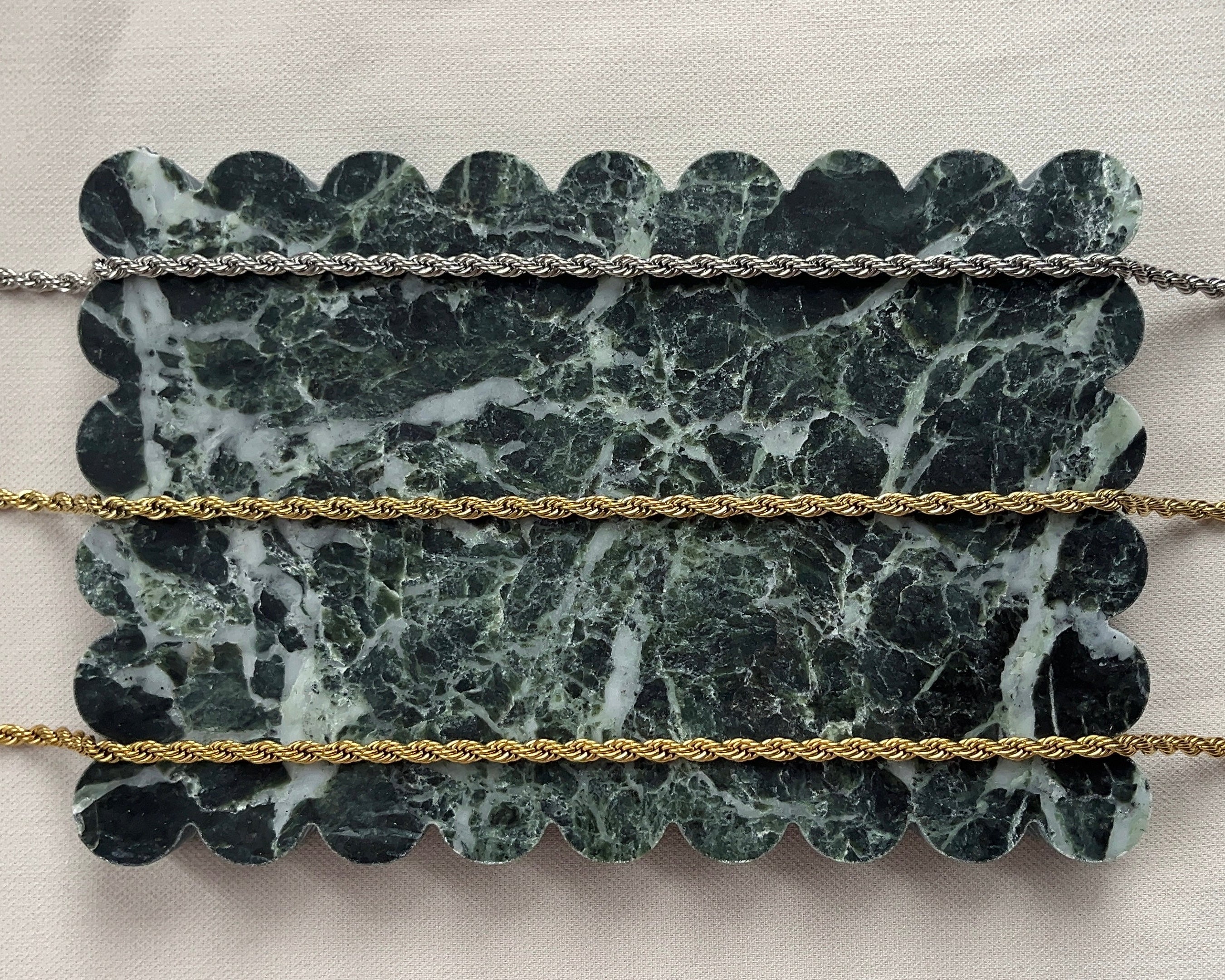 Marble-patterned stone with gold and silver ropes on a light background
