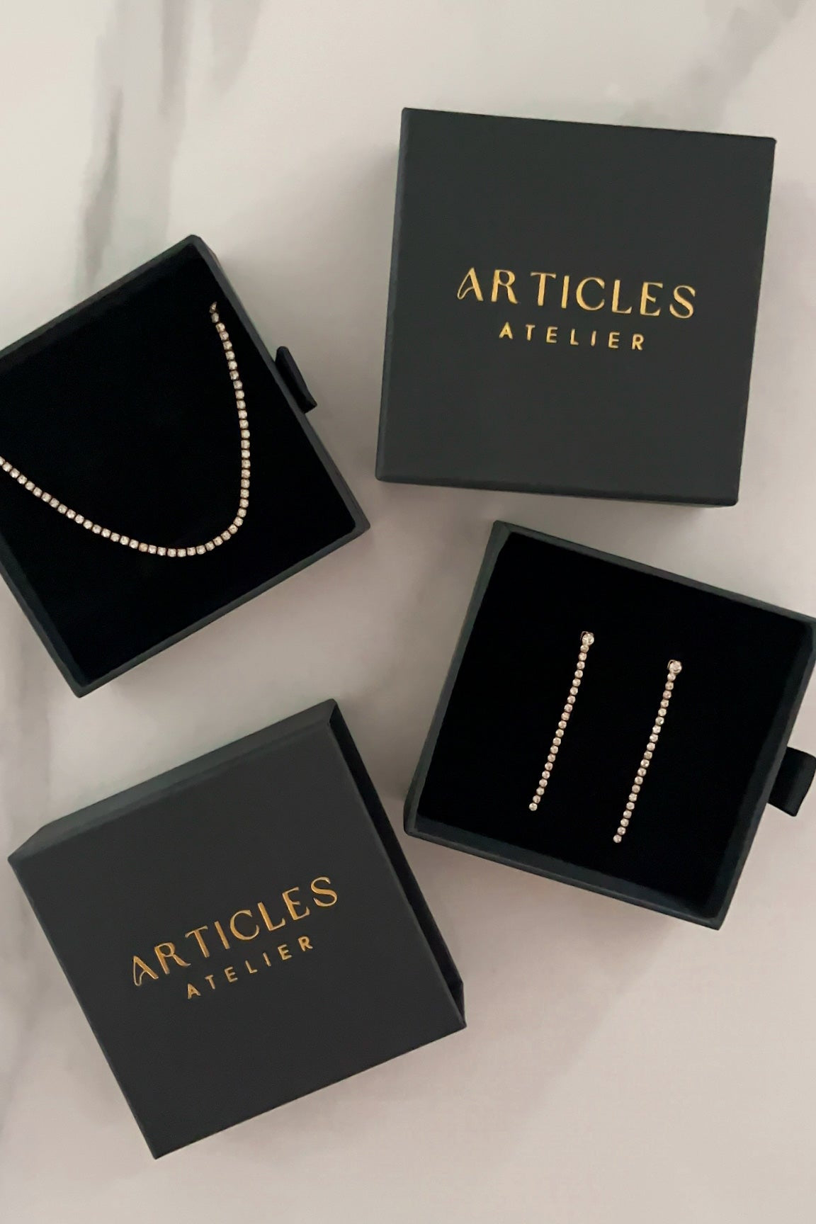 Jewelry set in 'Articles Atelier' boxes on a light background